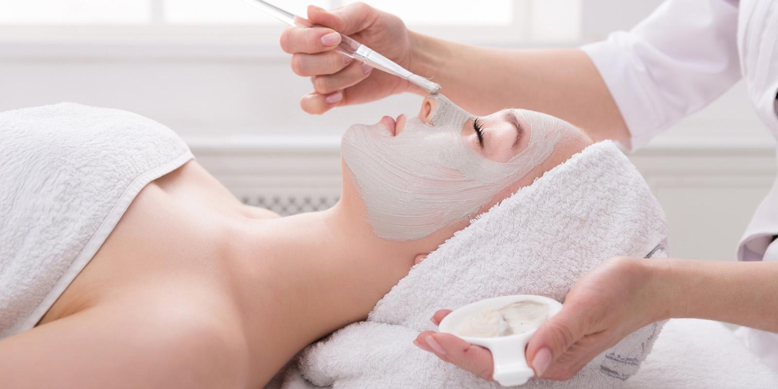 Woman gets face mask by beautician at spa
